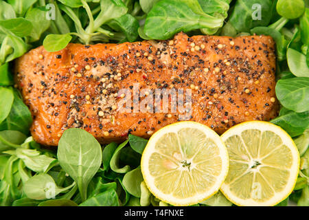 Salmone affumicato con le fette di limone e baby insalata di spinaci Foto Stock