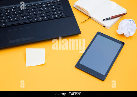 Tablet e un computer portatile su sfondo giallo Foto Stock