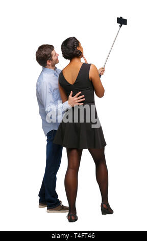 Vista posteriore di un interracial giovane che rende selfie su selfie stick. bella ragazza cordiale e guy insieme. Vista posteriore di raccolta persone. retro Foto Stock