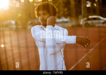 Bel giovane stiramento durante outdoor training Foto Stock