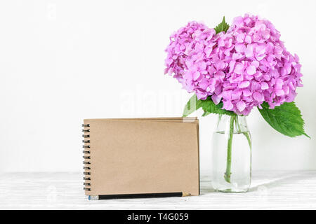 Nozze carta craft card con profumo di rosa fiori di ortensie in vaso. mock up. vacanza di primavera o nozze background. still life Foto Stock