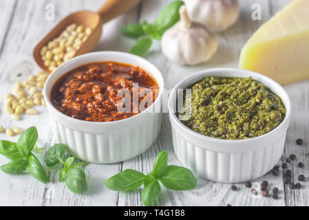 Bocce di classico e pomodori secchi pesto con ingredienti in bianco sullo sfondo di legno Foto Stock