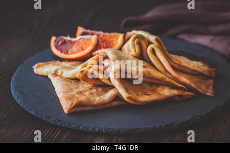 Crepes Suzette con fettine di arancia rossa sulla pietra nera board Foto Stock