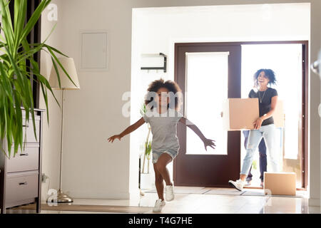 Felice famiglia americana africana con scatole di cartone nella nuova casa Foto Stock