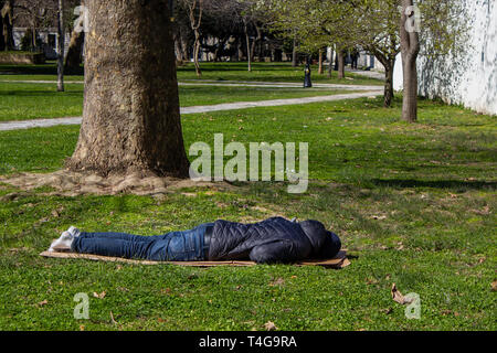 Senzatetto uomo dorme nel parco sdraiato sul pavimento Foto Stock