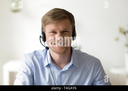 Ritratto di bello uomo sorridente lavorando nelle cuffie in ufficio Foto Stock