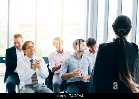 Vista posteriore della donna elegante dando presentazione per i colleghi che lavorano insieme in ufficio Foto Stock