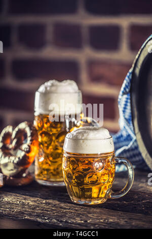 Oktoberfest grandi e piccole birra con pretzel Barile di legno e tovaglia blu. Foto Stock