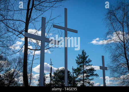 Tre croci nel bosco di alberi contro un nuvoloso cielo blu simbolica della Pasqua e della crocifissione di Cristo e la resurrezione visto closeup angolo basso Foto Stock