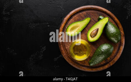 Affettato e intera avocado e l'olio nella coppa a bordo Foto Stock