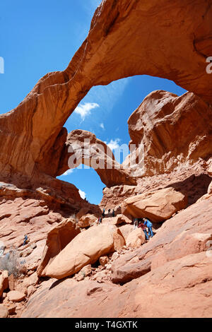 Visitatori escursione il sentiero di sabbia per salire la soggezione ispiratore per il doppio arco a Gli Archi Nazione Park in Utah, Stati Uniti d'America. Foto Stock