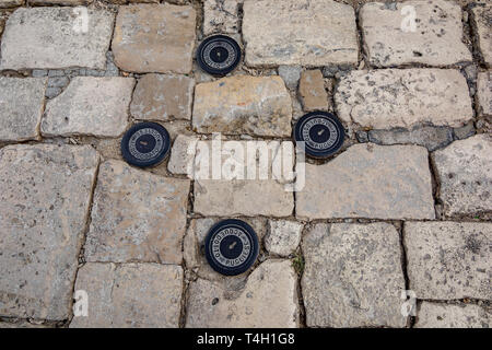 Quattro piccoli black iron chiusini a Matera, Italia, pubblica lastricato in pietra street nella città vecchia. Moody giorno di estate Foto Stock