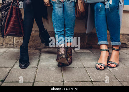 Tre donne che indossano scarpe alla moda, abbigliamento e accessori esterni. Bellezza fashion concept. Foto Stock