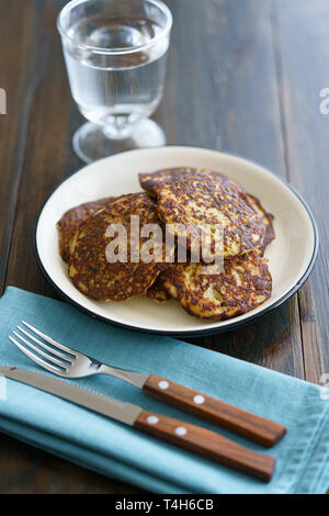 Frittelle di patate draniki servita su una piastra bianca. Dark tavolo in legno e biancheria blu igienico, ad alta risoluzione Foto Stock