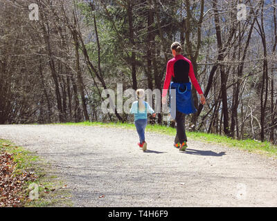 Madre con bambina figlia escursionismo e divertirsi e beeing felici insieme. Viaggio di famiglia dal lago in una foresta a molla. Foto Stock