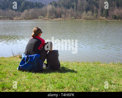Madre e figlio dal lago guardando acqua e foreste beeing rilassato come la meditazione nella natura Foto Stock