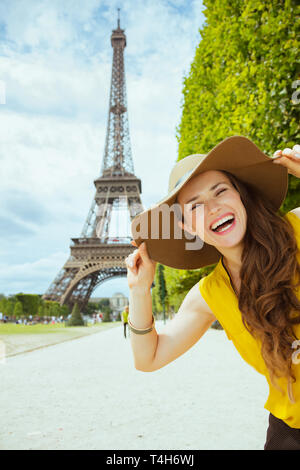 Ritratto di Allegro elegante viaggiatore donna in giallo camicetta e hat contro chiara vista della Torre Eiffel a Parigi, Francia. Foto Stock