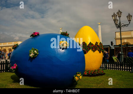 Grande blu e giallo decorato le uova di pasqua a pasqua mercato vicino al Palazzo di Schonbrunn a Vienna e persone che acquistano souvenir di Pasqua Foto Stock