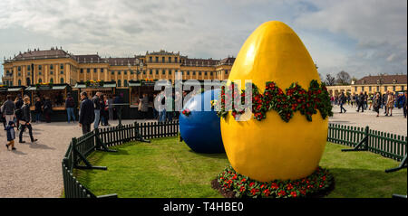 Grande blu e giallo decorato le uova di pasqua a pasqua mercato vicino al Palazzo di Schonbrunn a Vienna e persone che acquistano souvenir di Pasqua Foto Stock