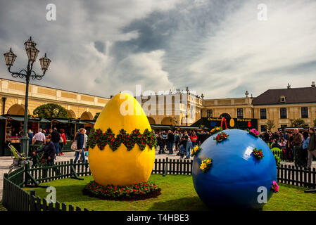 Grande blu e giallo decorato le uova di pasqua a pasqua mercato vicino al Palazzo di Schonbrunn a Vienna e persone che acquistano souvenir di Pasqua Foto Stock