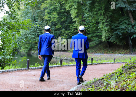 2 giovani uomini, Hasidic ebrei in tute blu e tappo bianco a piedi in Uman. Ucraina, durante l'anno ebraico. Foto Stock