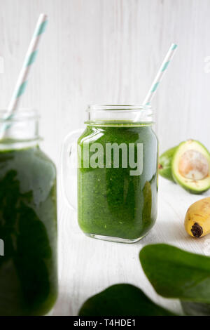 Frullato di verde con spinaci, avocado e banana in vasetti di vetro, vista laterale. Primo piano. Foto Stock