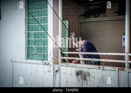 Pescatore non identificato al ponte del traghetto Star di Tsim Sha Tsui. Il pescatore cinese utilizza pesce pesca con la canna da pesca nel mare al Victoria Harbour Foto Stock