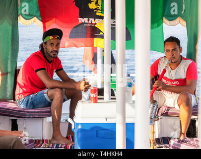 Aswan, Egitto - 13 Settembre 2018: egiziana uomini fumatori shisha tubo mentre la vela in un motoscafo turistica nel fiume Nilo Foto Stock