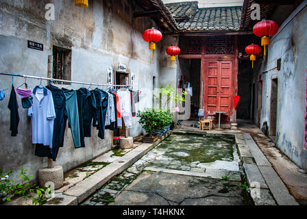 Lavanderia a secco, cortile di una casa tradizionale cinese. La lavanderia si blocca per asciugare all'esterno, casa con tetto in piastrelle. Lanterne rosse, Cina, Interni, povertà Foto Stock