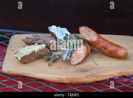 16 aprile 2019, il Land Brandeburgo, Fürstenwalde: Herb salsiccia affumicata alla brace rivestita con forno in pietra pane con lardo vegetariano (l-r), cinghiale salsiccia di fegato e di erbe selvatiche di ricotta sono serviti su una scheda. Il cibo è stato preparato dal Gasthof Reuner da Glashütte. Foto: Patrick Pleul/dpa-Zentralbild/ZB Foto Stock