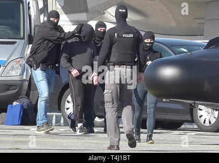 Amburgo, Germania. Xvii Apr, 2019. Un elemento di sospetto della milizia terroristica è (secondo da sinistra) è portato a un elicottero della polizia federale presso l'Aeroporto di Amburgo. Il piano sarà in grado di volare il sospetto di Karlsruhe, dove un giudice istruttore presso l'Alta Corte federale deciderà in merito all'esecuzione della detenzione in attesa di processo. Credito: Bodo segna/dpa/Alamy Live News Foto Stock