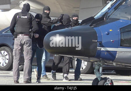 Amburgo, Germania. Xvii Apr, 2019. Un elemento di sospetto della milizia terroristica è (secondo da destra) è portato a un elicottero della polizia federale presso l'Aeroporto di Amburgo. Il piano sarà in grado di volare il sospetto di Karlsruhe, dove un giudice istruttore presso l'Alta Corte federale deciderà in merito all'esecuzione della detenzione in attesa di processo. Credito: Bodo segna/dpa/Alamy Live News Foto Stock