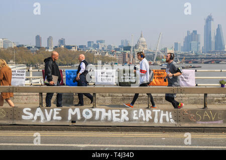 Londra, Regno Unito. Xvii Apr, 2019. I pedoni a piedi sul ponte di Waterloo coperto di graffiti di messaggi al giorno 3 della ribellione di estinzione protesta come parte di una protesta in corso per costringere il governo britannico a dichiarare una crisi climatica emergenza in 2 settimana di campagna Credito: amer ghazzal/Alamy Live News Foto Stock