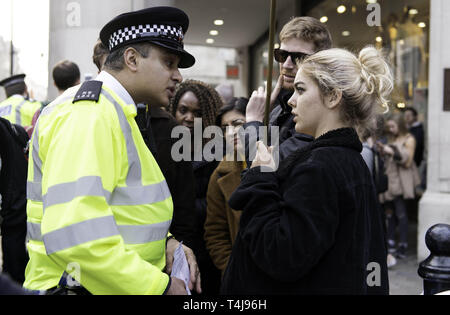 London, Greater London, Regno Unito. Xvii Apr, 2019. Funzionario di polizia è visto parlare con un attivista durante la ribellione di estinzione sciopero a Londra.gli attivisti ambientali dalla ribellione di estinzione movimento tenere premuto per il terzo giorno consecutivo Oxford Circus a Londra. Gli attivisti è stata parcheggiata una rosa di barca in mezzo di Oxford Circus junction bloccando le strade e causare interruzioni, gli agenti di polizia sono stati arresto di manifestanti che si rifiutano di testa a Marble Arch. Estinzione della ribellione esige dal governo di azioni dirette sul clima, ridurre a zero le emissioni di carbonio entro il 2025. (Credito Foto Stock