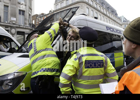 London, Greater London, Regno Unito. Xvii Apr, 2019. Funzionario di polizia è visto cercando di staccato di un manifestante che ammanettato se stesso a una polizia van durante la ribellione di estinzione sciopero a Londra.gli attivisti ambientali dalla ribellione di estinzione movimento tenere premuto per il terzo giorno consecutivo Oxford Circus a Londra. Gli attivisti è stata parcheggiata una rosa di barca in mezzo di Oxford Circus junction bloccando le strade e causare interruzioni, gli agenti di polizia sono stati arresto di manifestanti che si rifiutano di testa a Marble Arch. Estinzione della ribellione esige dal governo di azioni dirette sul clima, reduc Foto Stock