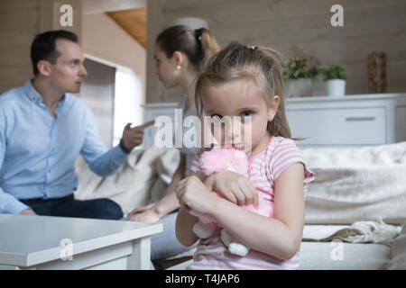 Triste bambina spaventata quando i genitori hanno lotta in casa Foto Stock