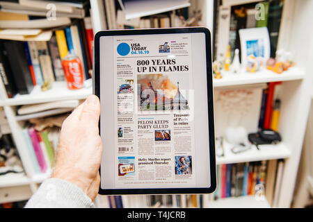 Parigi, Francia - Apr 15, 2019: l uomo la lettura di USA Today su iPad Apple Pro Plus News giornale digitale dotato di coperchio sulla Cattedrale di Notre Dame a fuoco causando danni 800 anni in fiamme Foto Stock