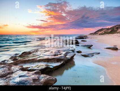 Coste calcaree e piscine di roccia brucia in spiaggia al tramonto. Perth, WA Foto Stock