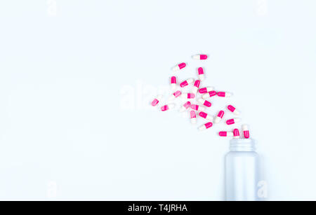 Rosa-bianco capsula di antibiotico pillole sparse fuori di plastica bianca flacone di farmaco. Farmaco antibiotico resistenza concetto. Farmaci antibiotici utilizzare. La salute globale Foto Stock