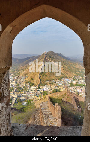 Antica parete lunga con torri intorno al Forte Amber attraverso l'arco delle pareti della torre. Jaipur. Il Rajasthan. India Foto Stock