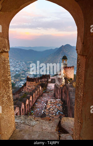 Antica parete lunga con torri intorno al Forte Amber attraverso l'arco delle pareti della torre al mattino. Jaipur. Il Rajasthan. India Foto Stock