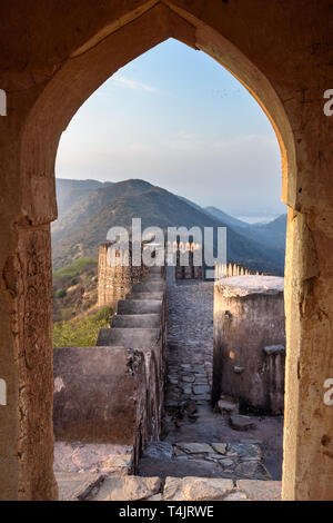 Antica parete lunga con torri intorno al Forte Amber attraverso l'arco delle pareti della torre. Jaipur. Il Rajasthan. India Foto Stock