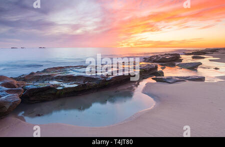 Coste calcaree e piscine di roccia brucia in spiaggia al tramonto. Perth, WA Foto Stock