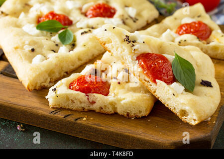 Italiano tradizionale focaccia con rosmarino, pomodori e feta - close-up piatti fatti in casa pane focaccia. Foto Stock