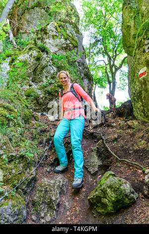 Giovane donna sulla radice impegnativo sentiero nel bosco Foto Stock