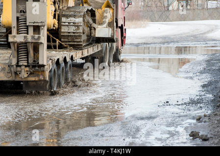 Onda sporca di spruzzo da sotto le ruote di un carrello. Acqua sulla strada. Foto Stock