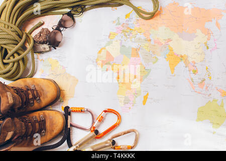 Attrezzatura per alpinismo in alta montagna: stivali, sport funi, carabine sullo sfondo di una mappa geografica. Foto Stock