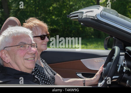 Felice coppia di anziani di unità con una lussuosa auto convertibili Foto Stock