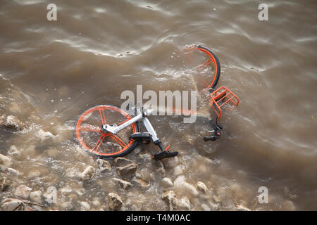 Acqua di fiume lambisce un scartato Mobike noleggio bici sul litorale gettato nel fiume Tamigi da vandali nei pressi di Westminster Bridge Foto Stock