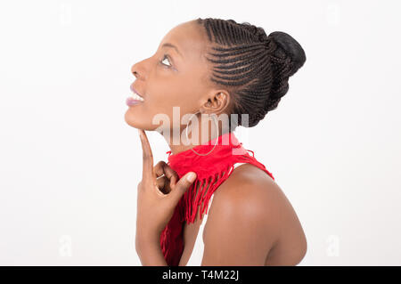 Felice e accorata donna con una bella pelle indossa una sciarpa rossa intorno al collo e si siede nel profilo guardando al di sopra di lei su uno sfondo luminoso Foto Stock